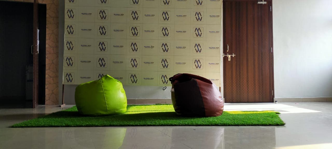 Bean bags on turf in front of the Millennial Worx backdrop